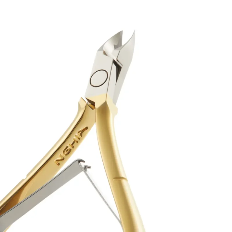 Product Name: Nghia Cuticle Nipper C-118 (D-501) Jaw 16 gold and silver nail clippers cutting a nail, isolated on a white background.