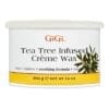 A white container of GiGi Tea Tree Creme Wax, 14 oz (396 g), featuring a label with green tea tree leaves. The product mentions "soothing formula" and "formule calmant" on the label, highlighting the calming properties of GiGi Tea Tree Creme Wax.