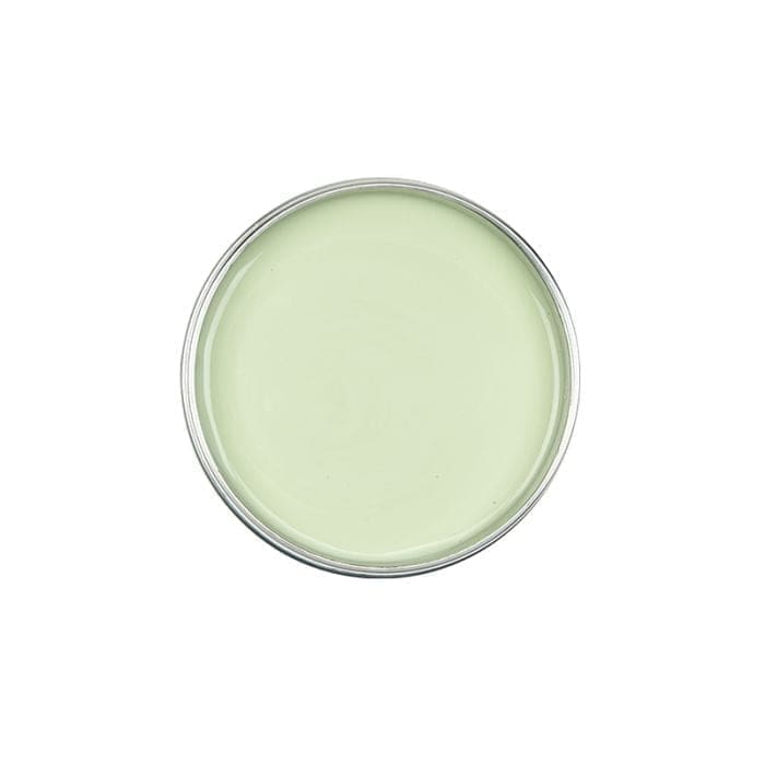 A top-down view of an open paint can filled with light green paint, resembling the soothing hue of GiGi Tea Tree Creme Wax.