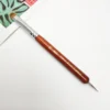 A KYE French Brush with Dotting Tool with a wooden handle used for painting on a piece of paper.