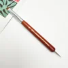 A KYE French Brush with Dotting Tool with a wooden handle on top of a book.