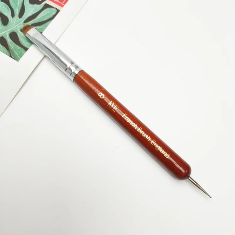 A KYE French Brush with Dotting Tool with a wooden handle on top of a book.