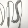 A coiled cord and a pair of wires on a white surface.