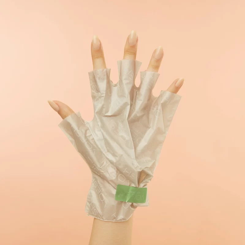 A woman holding a pair of Voesh Collagen Gloves With Cannabis Sativa Seed Oil on a peach background.