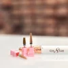 A close-up of four Cre8tion 5 in 1 Long Bit (3/32") with pink holders and a white nail drill handle also labeled "Cre8tion" resting on a white surface. The background is blurred.