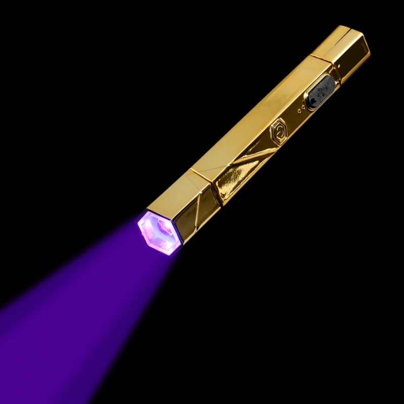 A gold-colored Apres Gel-x Flash Cure Omni Light Gold emitting a purple beam against a black background.