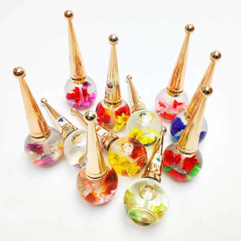 A group of decorative KYE Flower Cuticle Oil 0.9oz bottles with gold pointed caps, each containing vibrant flower designs inside the transparent liquid.