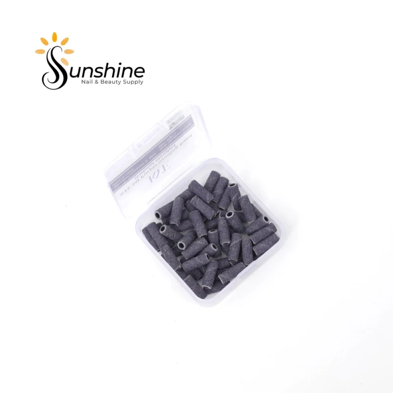 A clear plastic container filled with 50pcs of cylindrical black nail sanding bands, labeled "KYE Small Premium Grade 3M Purple Sanding Band 50pcs/Box", includes premium grade 3M Purple Sanding Bands.