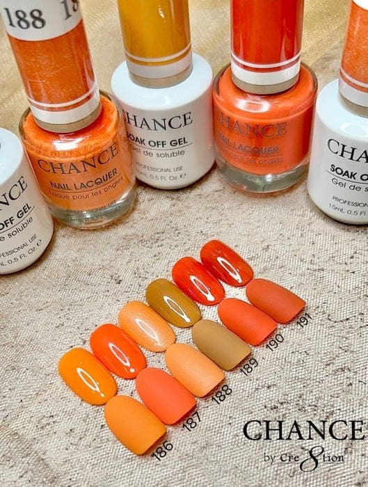 A display of orange and yellow nail polishes labeled "CHANCE Matching Trio - Autumn Spice Collection (36 Colors)" with matching artificial nail tips numbered 186 to 191, shown on a textured beige surface.