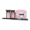 This image shows the Gelish Solid Cream Gel Polish Starter Kit - BLUSH, featuring a pink nail curing lamp, two small open compact cases with nail powders, and a black-handled nail brush labeled "Gelish," perfect for anyone starting their gel polish journey.
