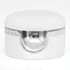 A white, cylindrical container with a clear, curved cutout section revealing a shiny, reflective interior; perfect for holding your Gelish Solid Cream Gel Polish from the Starter Kit - BOLD.