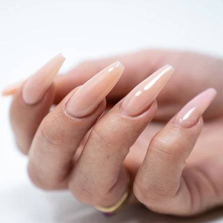 A close-up of a hand with long, almond-shaped acrylic nails painted in a glossy nude color, enhanced with the YOUNG NAILS Protein Bond Non Acid 0.50oz for extra durability.